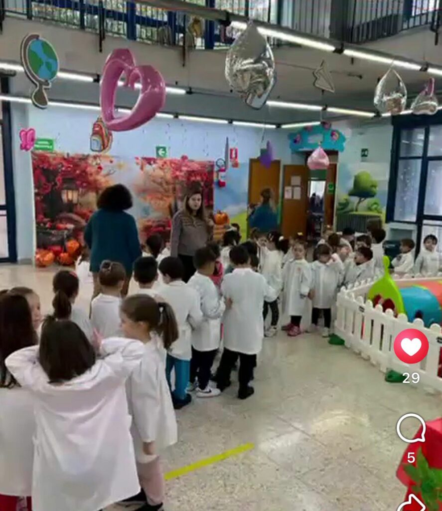 i piccoli alunni in fila davanti al grande pannello che rappresenta un bosco autunnale con una pila di zucche